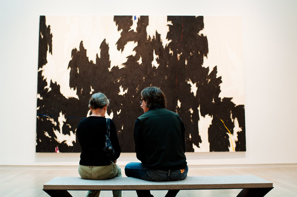 Art enthusiasts sit in front of an original Clyfford Still.