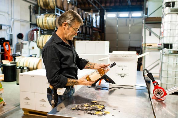 Mile High Spirits CEO Rich Harris double checks the bottles of Fireside Whiskey before packing them in boxes.