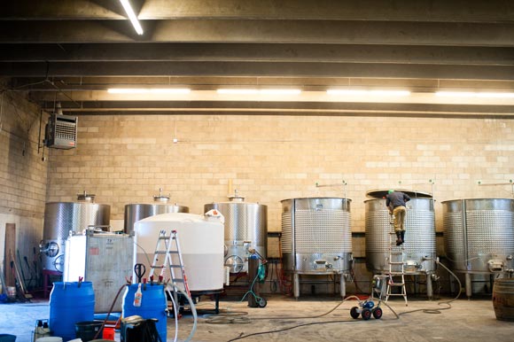 Cellar master Adam Teitelbaum checks the wine while skimming off the top layer of water.