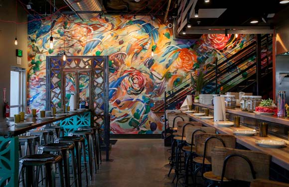 Los Chingones greets patrons with a colorfully chaotic floor-to-ceiling splatter painting.