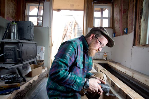 Marcus Hyde finishes a storage bench in a tiny house. 