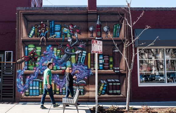 People walk past a mural outside BookBar. 