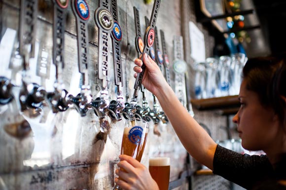 Bartender Lindsey Lee pours a beer at the Denver Beer Company in the Central Platte Valley.