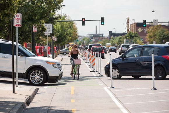 A cyclist maneuvers between two turning cars.